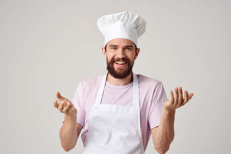Cheerful male chef in uniform cooking food kitchen light backgroundの写真素材
