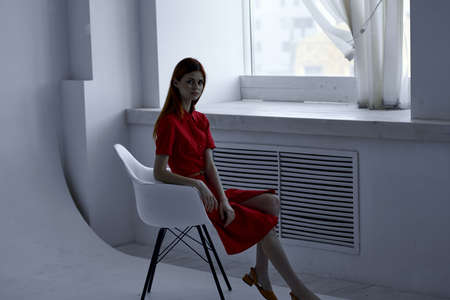 beautiful woman in red dress posing on a chair fashion