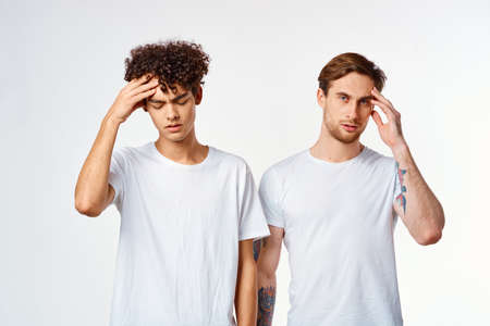 two guys in white t-shirts communication friendship light backgroundの写真素材