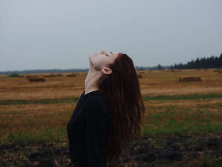 cute red-haired woman in black dress in field travel fashionの写真素材
