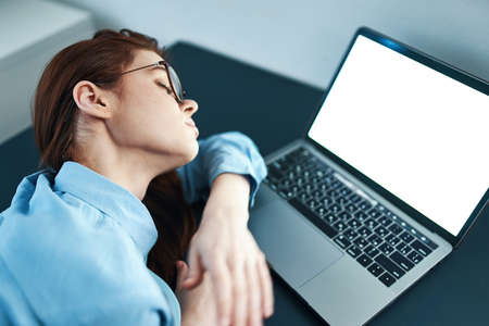 tired woman sitting at a table in front of a laptop work dissatisfaction
