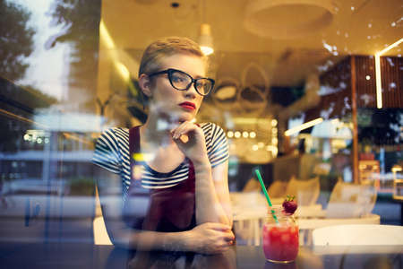 woman alone sitting in a restaurant cocktail vacation dreamy lookの写真素材