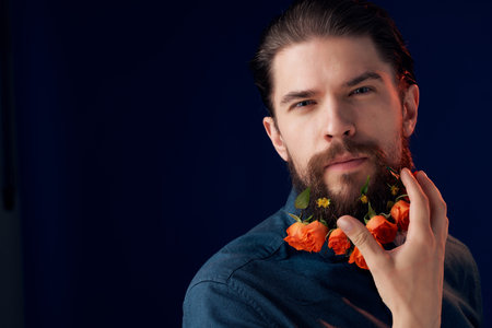 portrait of a man with flowers in a beard in a black shirt dark background