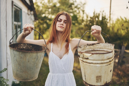 woman in white dress with buckets in hand nature Lifestyleの写真素材
