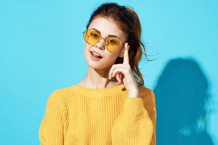 cheerful fashionable woman in yellow sweater posing fashion clothing blue backgroundの写真素材