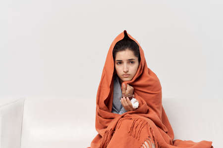 woman with an unhealthy look hiding behind a plaid at home treatment