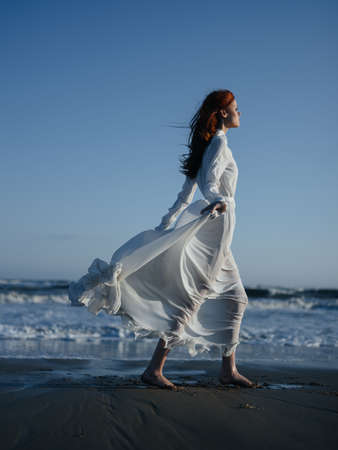Woman in white dress posing fashion walking along the beach vacation