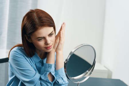 woman looks in the mirror hairstyle cosmetics morning clean skinの写真素材
