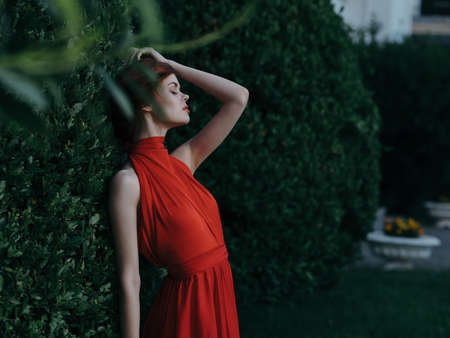 woman near bush in red dress and fairy garden decorationの写真素材