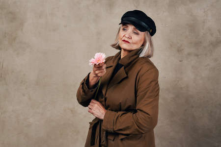 elegant elderly woman in coat holding a flower fashionの写真素材
