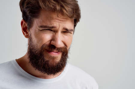 bearded man in a white t-shirt headache migraine problems isolated backgroundの写真素材
