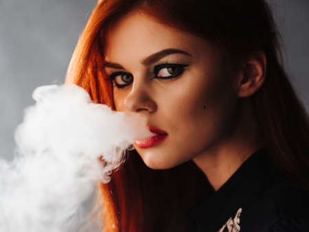 pretty woman bright makeup smoke from mouth studioの写真素材