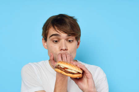 a man in a white t-shirt hamburger eating a snack food