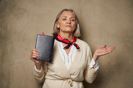 elderly woman in a dressing gown with a notebook in her hands studio work