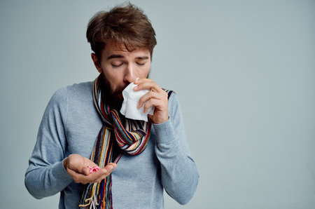 sick man in a sweater with a handkerchief infection light backgroundの写真素材