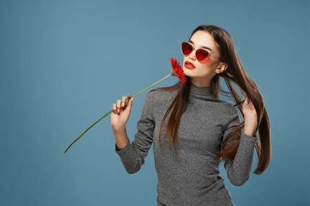 beautiful brunette sunglasses red flower near face cosmetics blue background