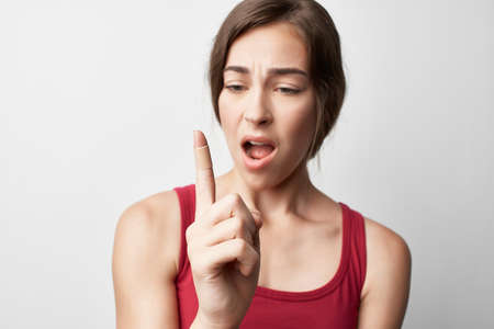 woman in red t shirt health problem injury fingers light backgroundの写真素材