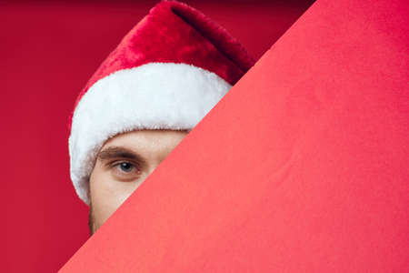 Cheerful man in a santa hat holding a banner holiday red backgroundの写真素材