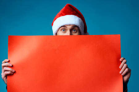 emotional man in a santa hat holding a banner holiday blue backgroundの写真素材