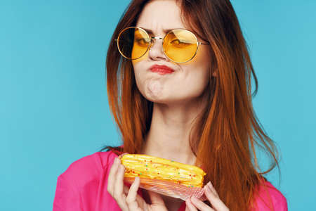 glamorous woman pink shirt with eclairs in the hands of sweetsの写真素材