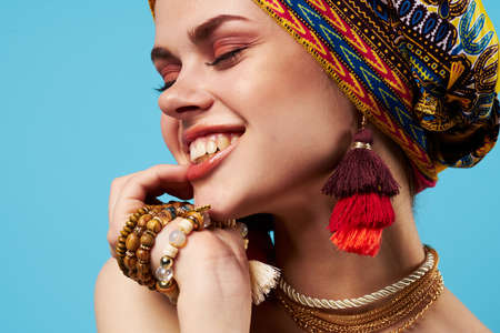 cheerful woman in multicolored turban attractive look Jewelry smile blue backgroundの写真素材