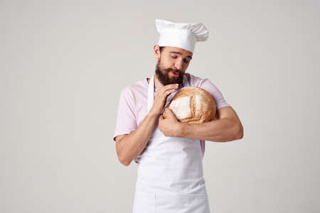 a man in a chefs uniform a baker with bread in his hands cookingの写真素材