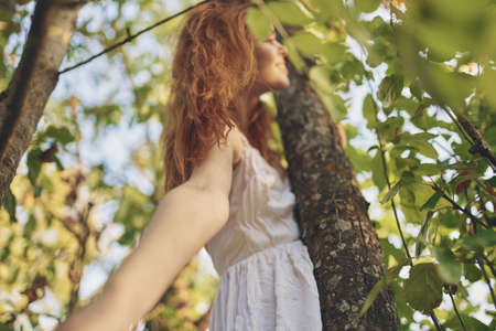 pretty woman in white dress nature green leaves of a tree bottom viewの写真素材