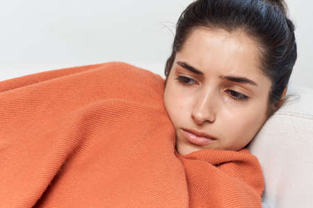 woman lying with closed eyes on the couch feeling unwell infectionの写真素材