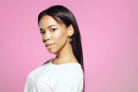pretty african woman long hair white t-shirt pink backgroundの写真素材