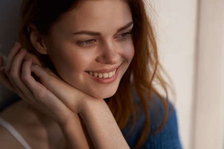 pretty woman sitting on the windowsill with a blue plaid dreamy lookの写真素材