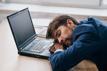 business man sleeping in front of laptop at his desk officeの写真素材