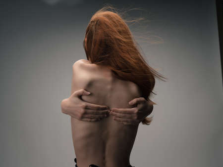 red-haired woman holding hands behind back back view figure