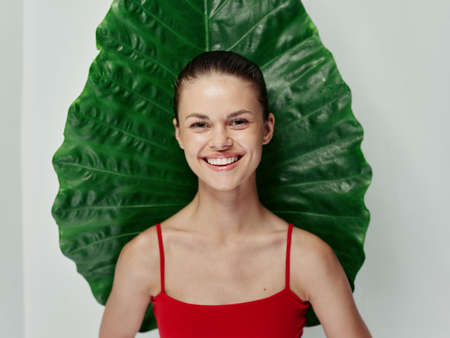woman in a red swimsuit smile green leaf exotic light background