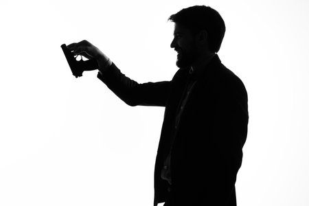 The man in a suit with a pistol in hand crime hand gesture light backgroundの写真素材