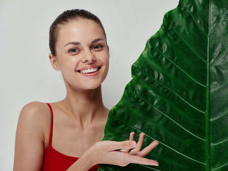 joyful woman with a green leaf of guys on a light background gesturing with her hands cropped viewの写真素材
