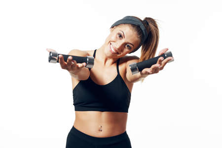 Strong woman wearing sportswear with dumbbells in hands on white background