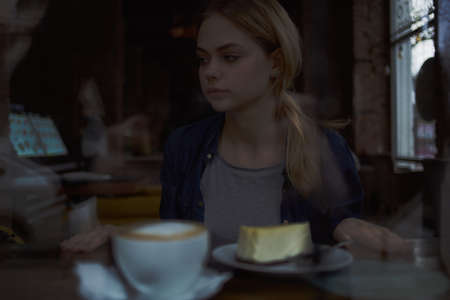 beautiful woman a cup of coffee in a cafe pensive lookの写真素材