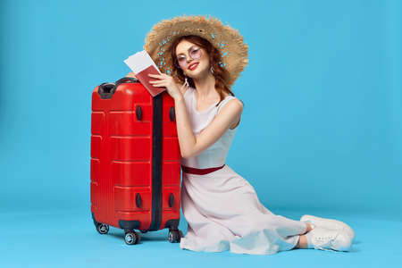 pretty woman in hat sitting on the floor with red suitcase travel destinationの写真素材