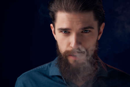 bearded man in a black shirt smoke clouds dark backgroundの写真素材