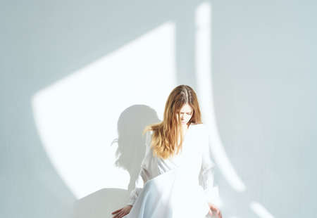 woman leaning against the wall wearing white dress isolated background romance