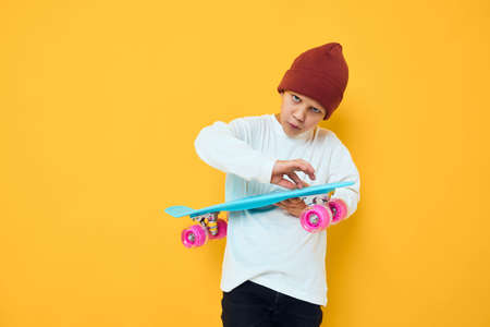 Cheerful little kid in a red hat skateboard in his hands studio posingの写真素材