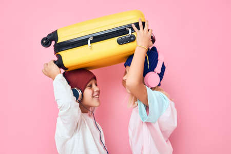 joyful boy and girl stylish clothes suitcase headphones Childhood lifestyle conceptの写真素材