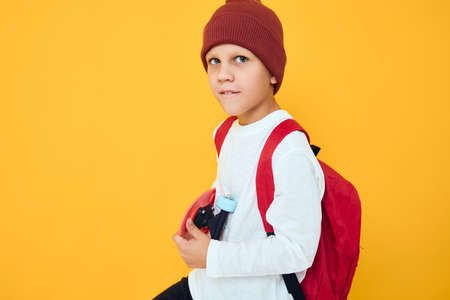 portrait of cute boys with red backpack red skateboard yellow color backgroundの写真素材