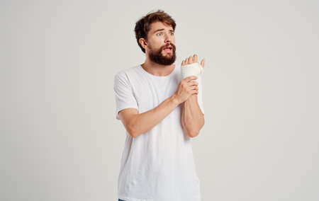 male patient in a white T-shirt with a bandaged hand posing hospital medicineの写真素材