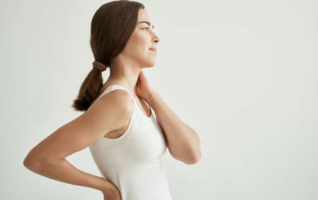 brunette in white t-shirt joint pain health problems dissatisfactionの写真素材