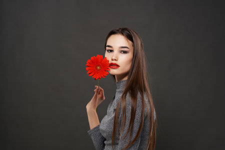 pretty brunette red flower near face makeup dark backgroundの写真素材