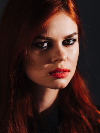 woman with makeup on her face red lips charm face close-up dark backgroundの写真素材