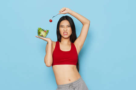 woman with novelty tomato and salad in plate red t-shirt blue backgroundの写真素材