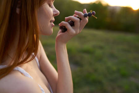 red-haired woman in nature in the field there are grapesの写真素材