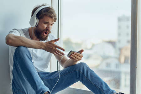 Man sitting on the windowsill in headphones in headphones restの写真素材